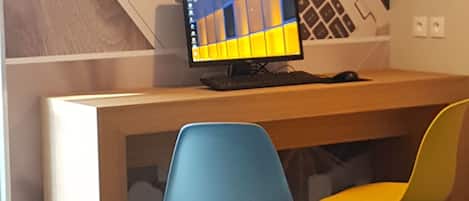 Un mostrador de recepción con un monitor de computadora, dos sillas y una pared con las palabras "webcorner" y un diseño geométrico.