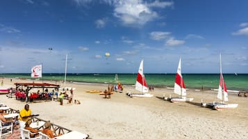Praia particular, areia branca, espreguiçadeiras, guarda-sóis