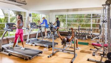 Une salle de sport équipée de tapis de course, d’un banc de développé couché et d’haltères.