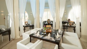 A dining area with white curtains, a glass table, and white chairs. - Tui Magic Life Penelope Beach (Djerba Midun)