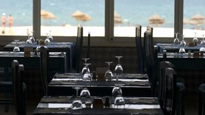 An empty restaurant with tables set for dining, large windows overlooking a beach, and umbrellas on the beach. - Yadis Morjane Tabarka (Tabarka)