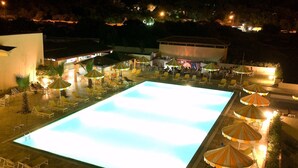 An outdoor swimming pool with lounge chairs and umbrellas, surrounded by buildings and trees. - Yadis Morjane Tabarka (Tabarka)