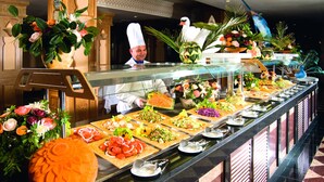 A buffet with various food items and a chef in the background. - Hotel Marco Polo (Hammamet)