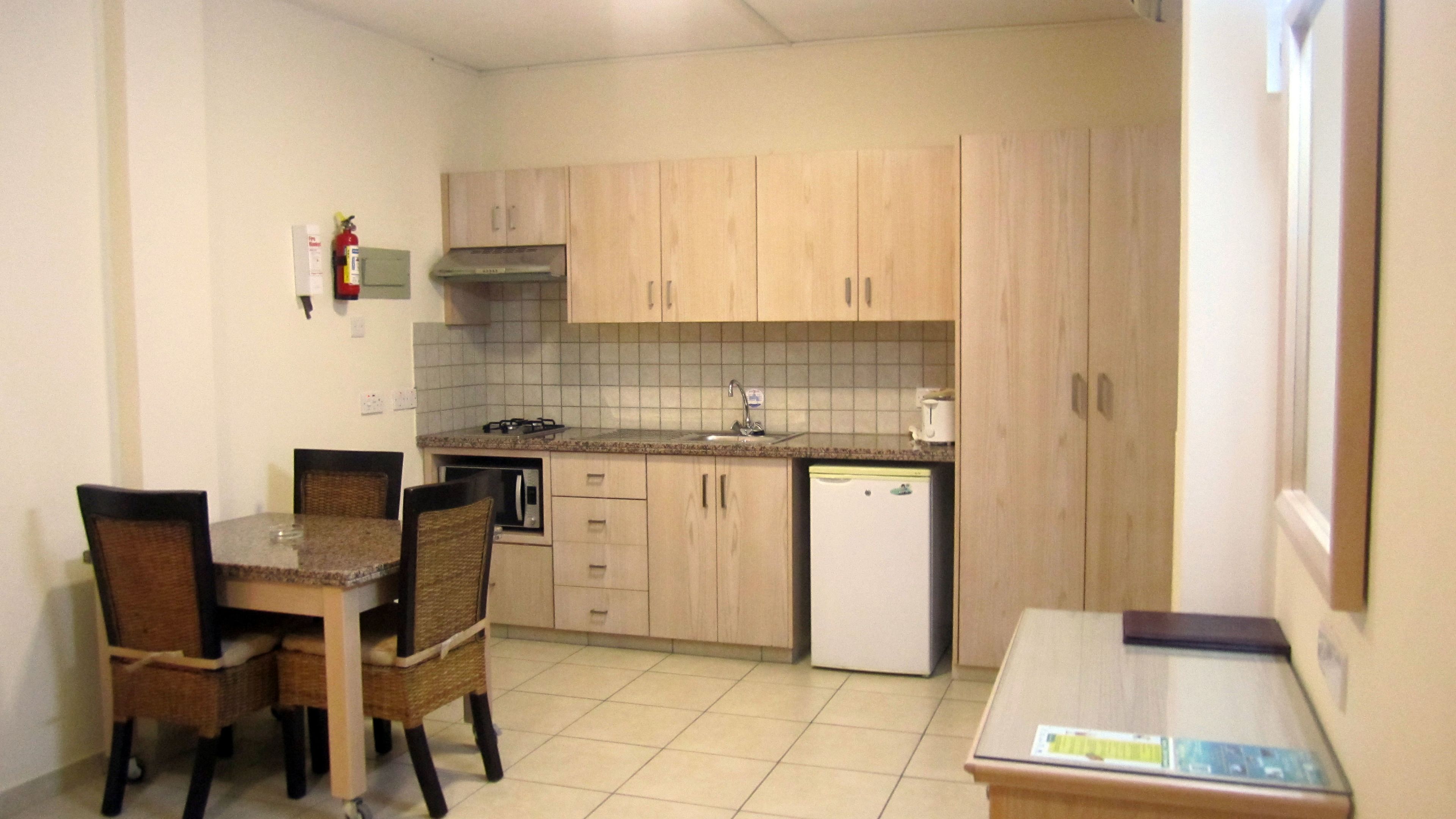 A compact kitchen with a dining table and chairs, a microwave, a stove, and a refrigerator.