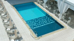 A rooftop pool with lounge chairs and umbrellas, surrounded by a covered area with tables and chairs. - Senator Hotel Apartments - Adults Only (Ayia Napa)
