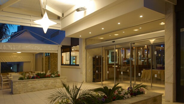 A lobby with a reception desk, seating area, and a glass door entrance. - Senator Hotel Apartments - Adults Only (Ayia Napa)