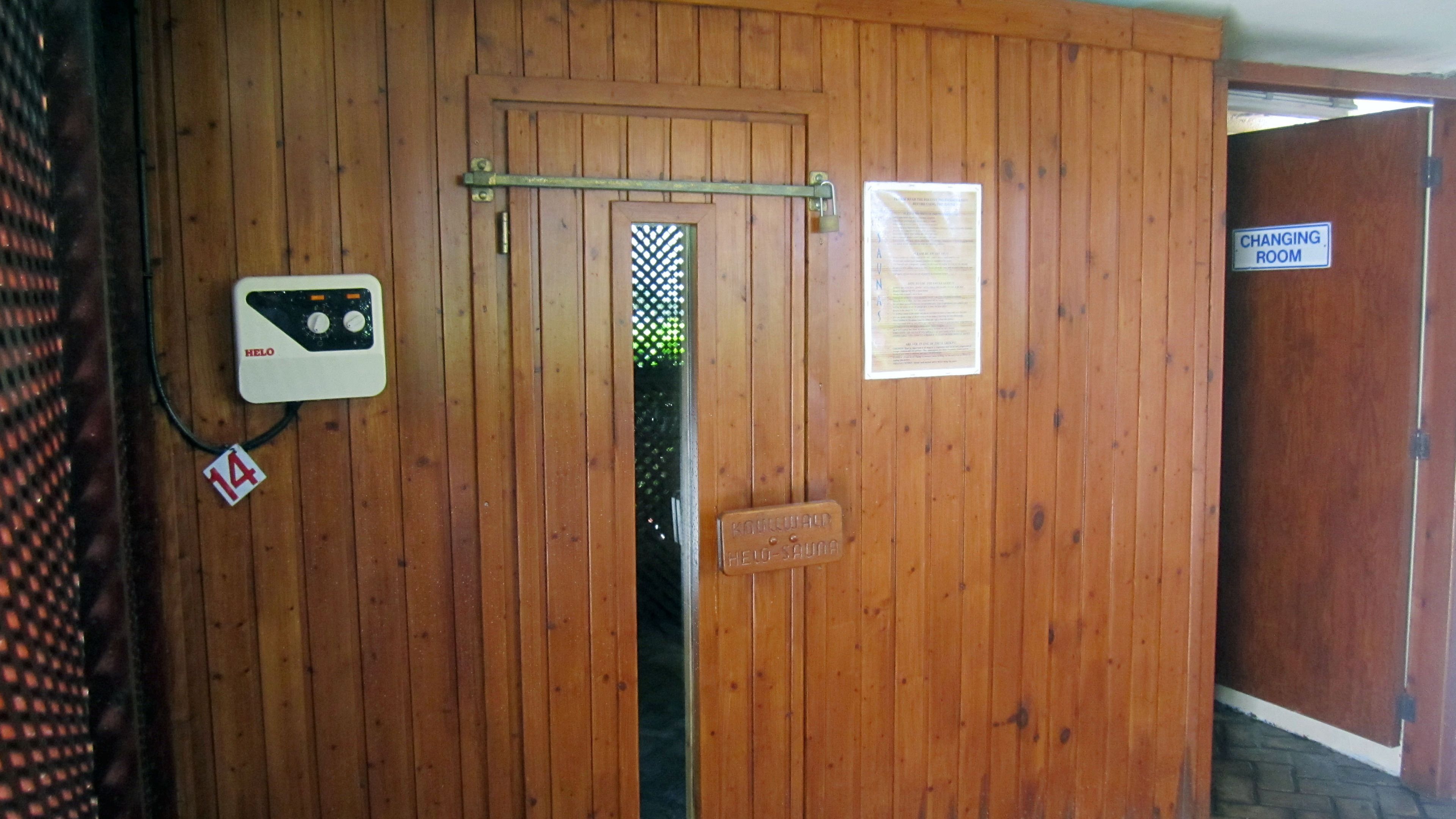 A wooden door with a sauna sign, a changing room sign, and a sauna control panel.