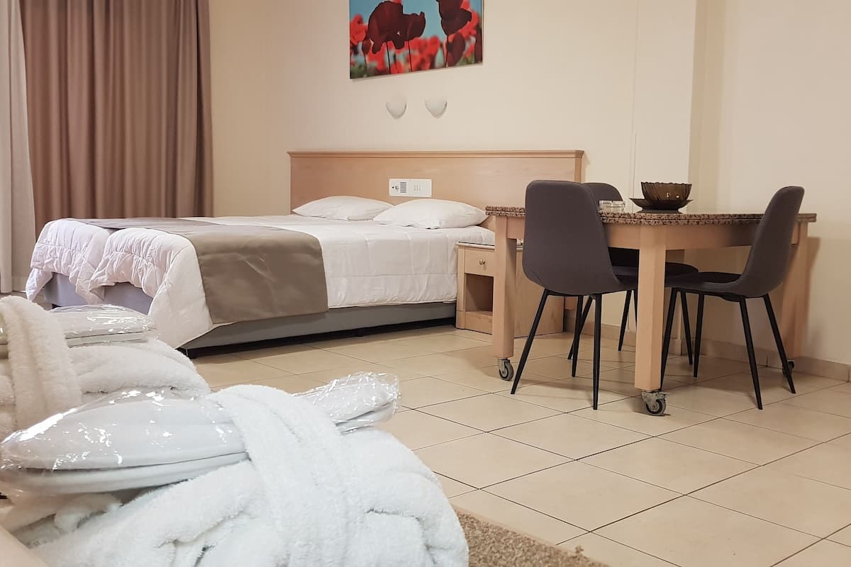Una camera d'albergo con un letto, una scrivania con sedie, un angolo cottura e un bagno.
