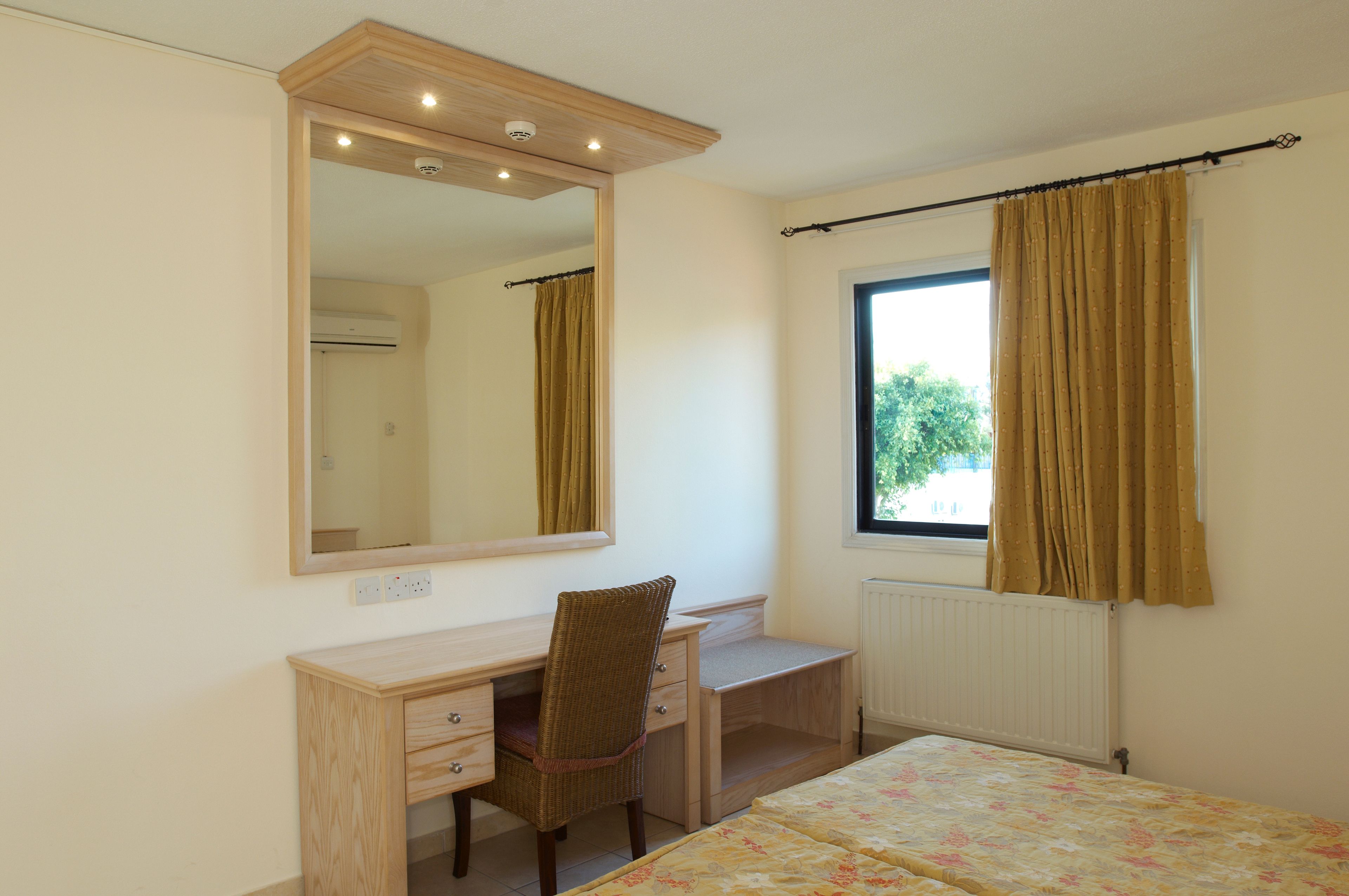 A bedroom with a wooden desk, chair, and a bed.