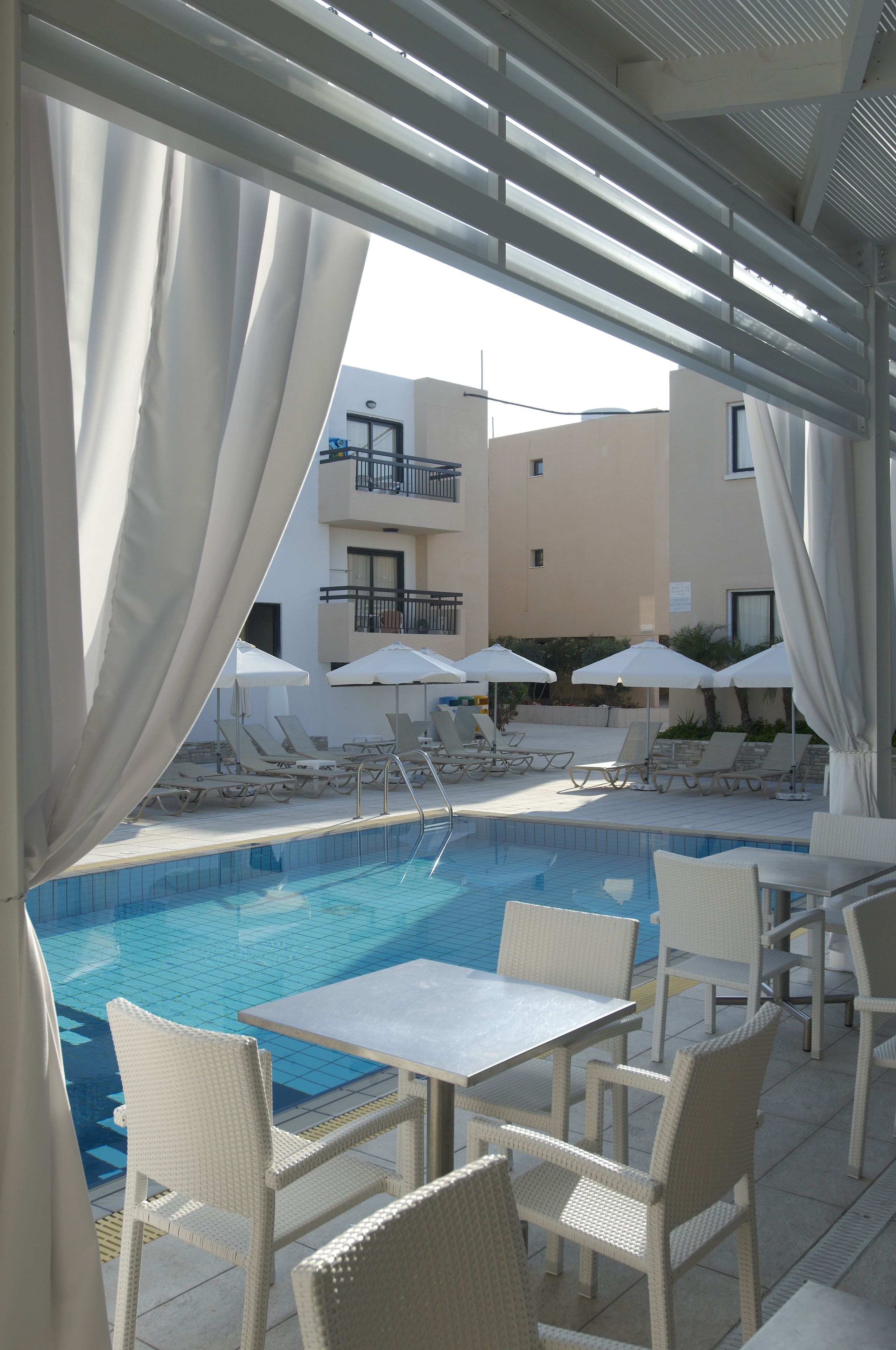 A poolside area with lounge chairs, umbrellas, and tables.