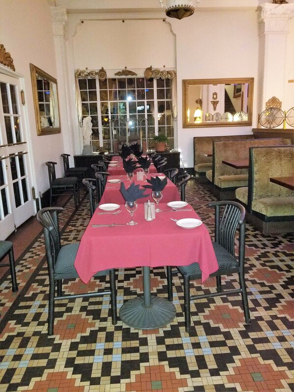 Un comedor con una mesa larga dispuesta para una comida, sillas y un suelo estampado.