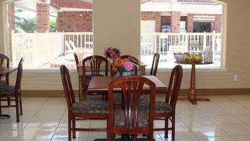 A dining area with a table set for six, surrounded by wooden chairs with floral upholstery.