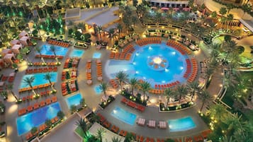 A large indoor pool area with multiple smaller pools and sun loungers arranged around them.