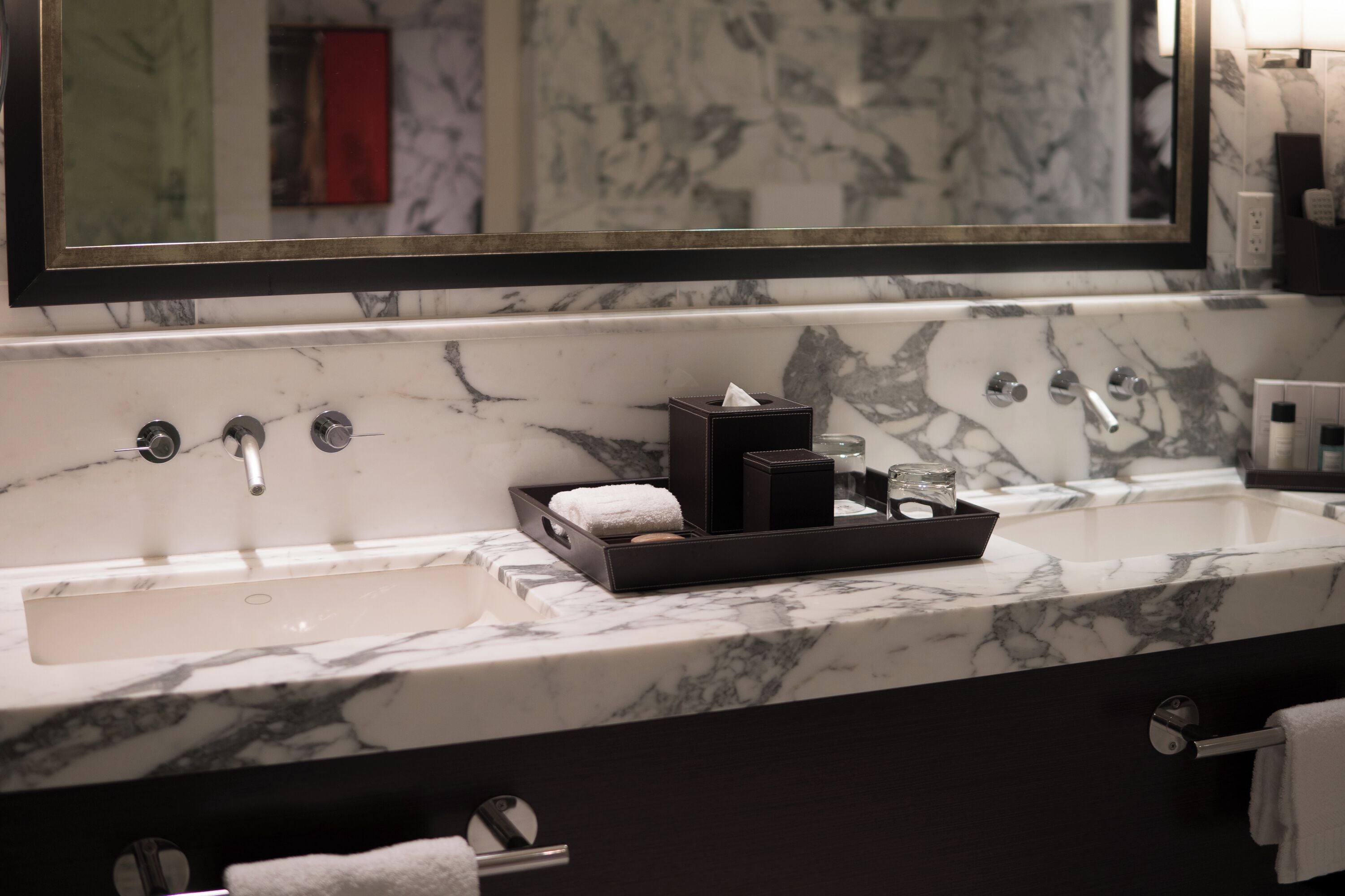 A bathroom with a marble sink, a large mirror, and a towel rack.