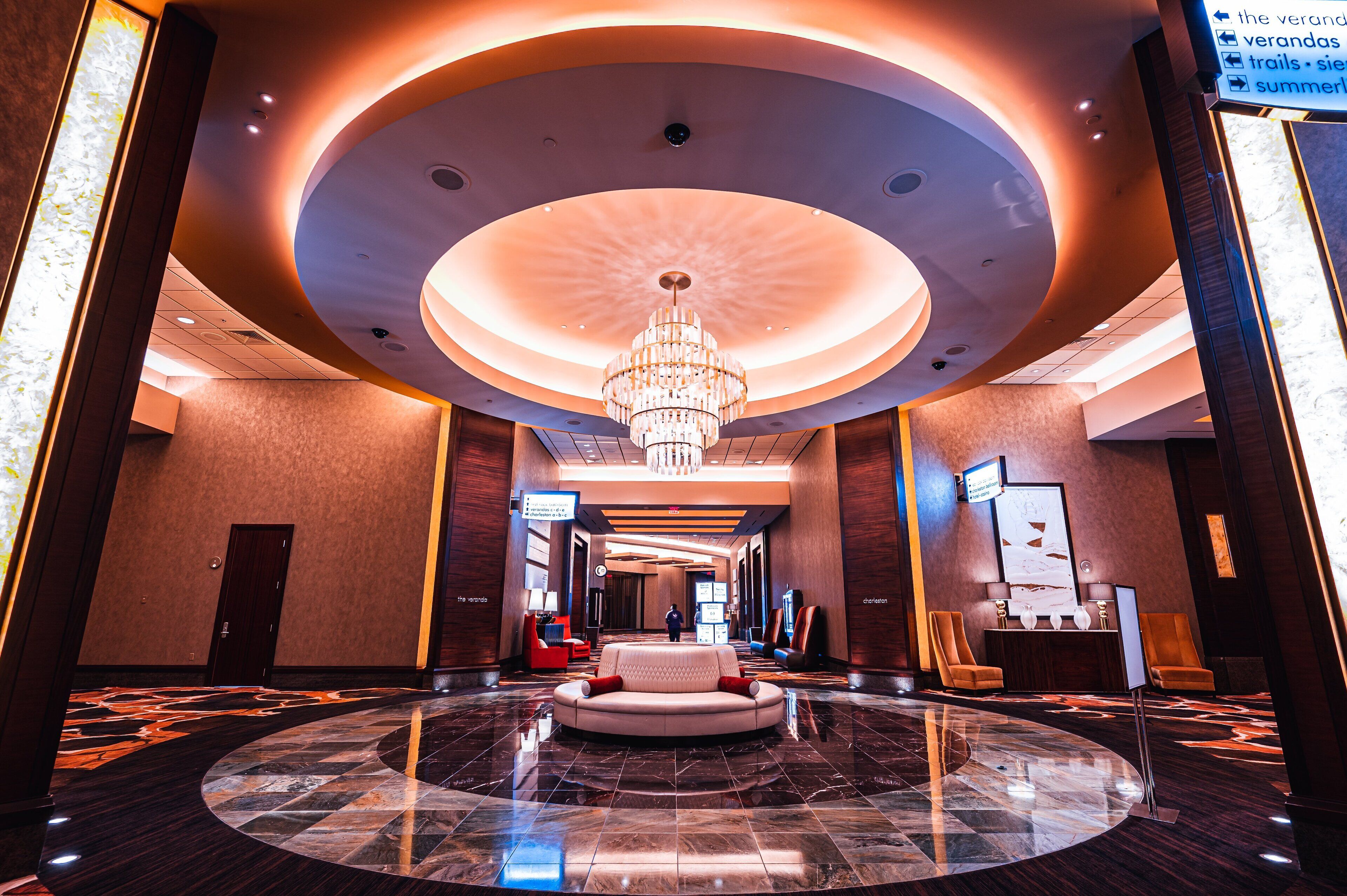 A spacious lobby with a central seating area, a chandelier, and a polished marble floor.