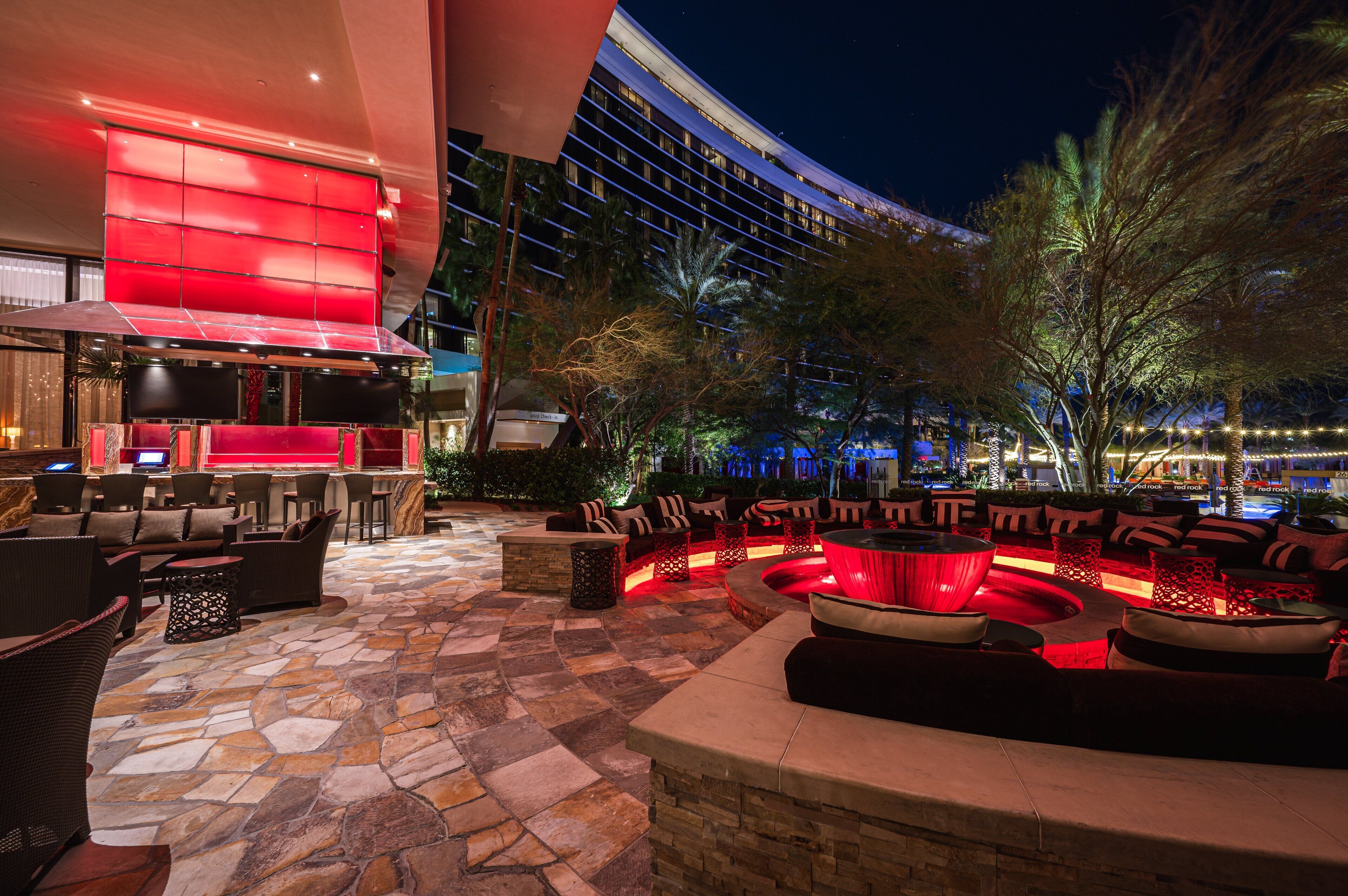 An outdoor lounge area with stone flooring, seating arrangements, and a modern building in the background.