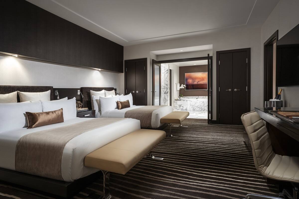 Een hotelkamer met twee bedden, een bank, een televisie en uitzicht op het omliggende landschap.