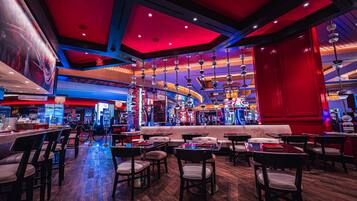 A spacious indoor area with multiple gaming machines, seating arrangements, and a prominent red curtain.