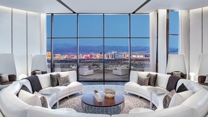Un salon moderne offrant une vue panoramique sur la ville, avec un canapé blanc, une table basse et une grande fenêtre.