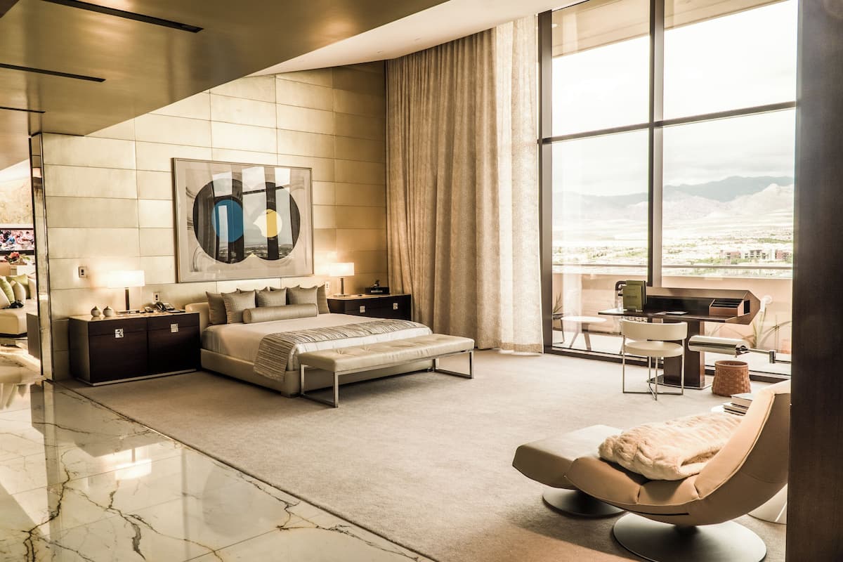 Een moderne hotelkamer met een groot bed, een zithoek en een bureau met uitzicht op de stad.