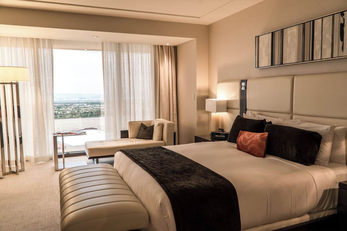 Een hotelkamer met een groot bed, een zithoek, uitzicht op de stad en een modern design.