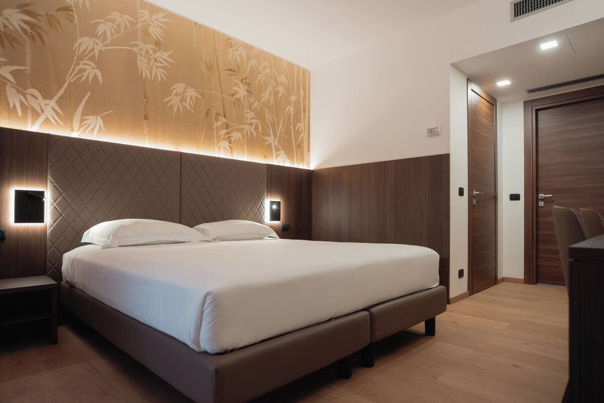 Un dormitorio moderno con una cama grande, paneles de madera e iluminación empotrada.