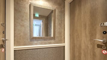 A hotel room with a wooden door, a mirror, and a textured wall.