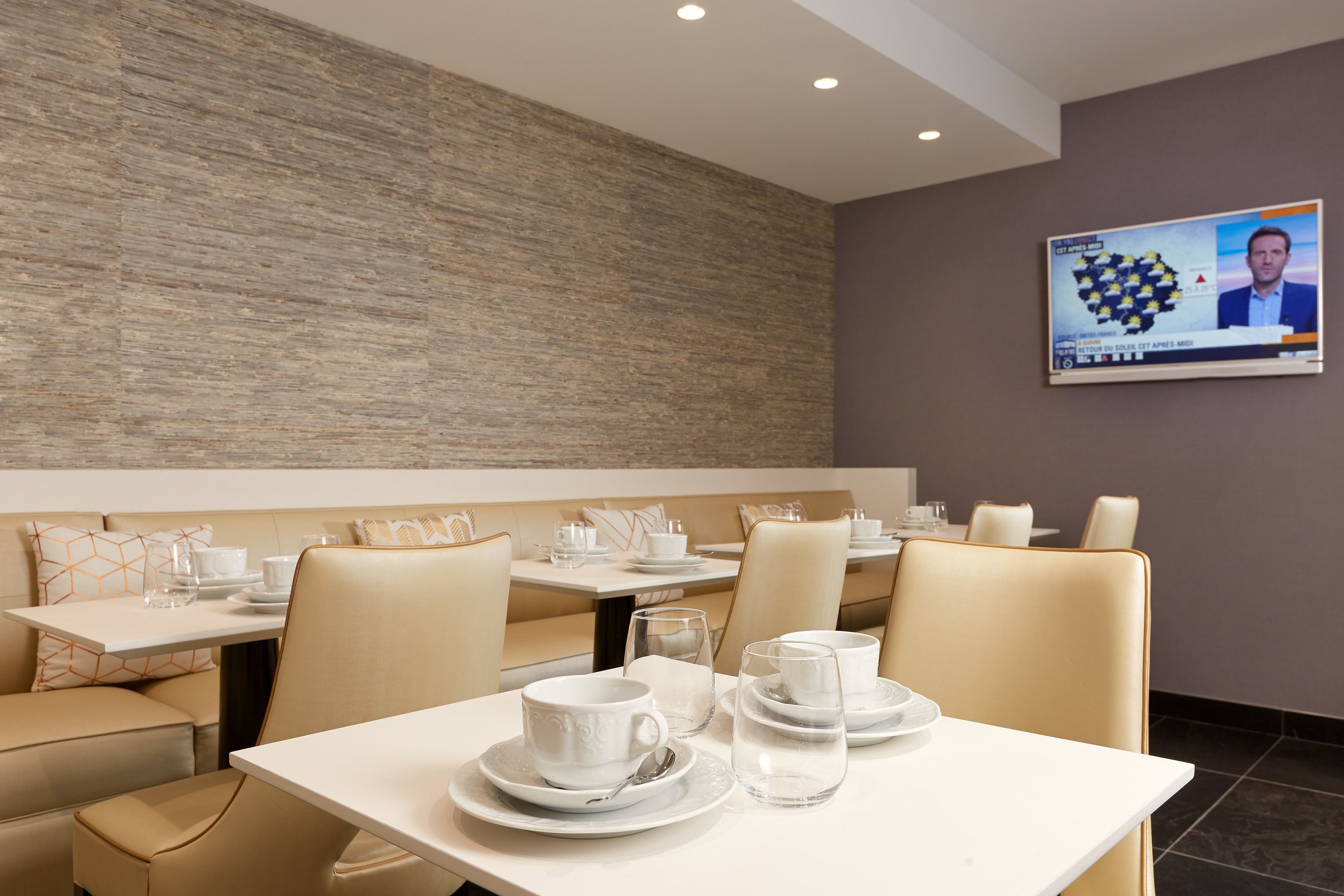 A modern dining area with booths and tables, equipped with white tableware and glassware.