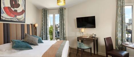 Habitación de hotel con una cama grande, un escritorio con silla, un televisor y vista a la ciudad.