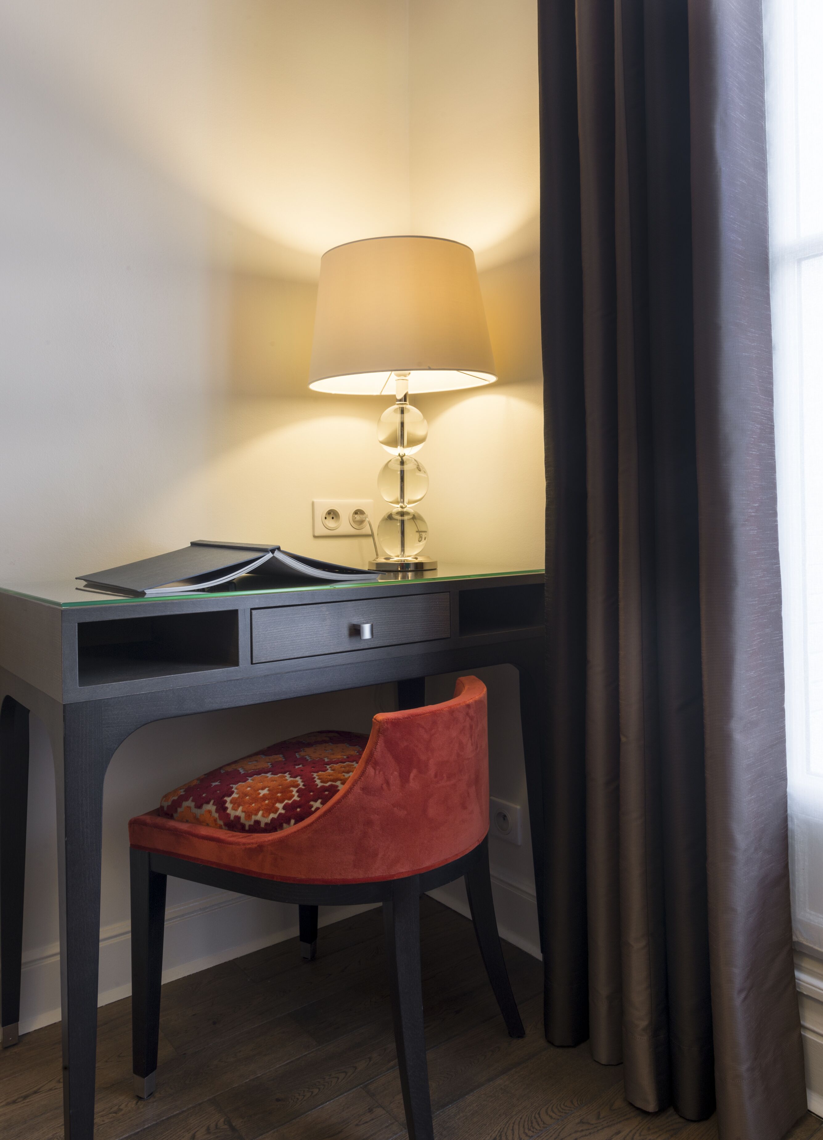A desk with a lamp, a chair, and a power outlet.