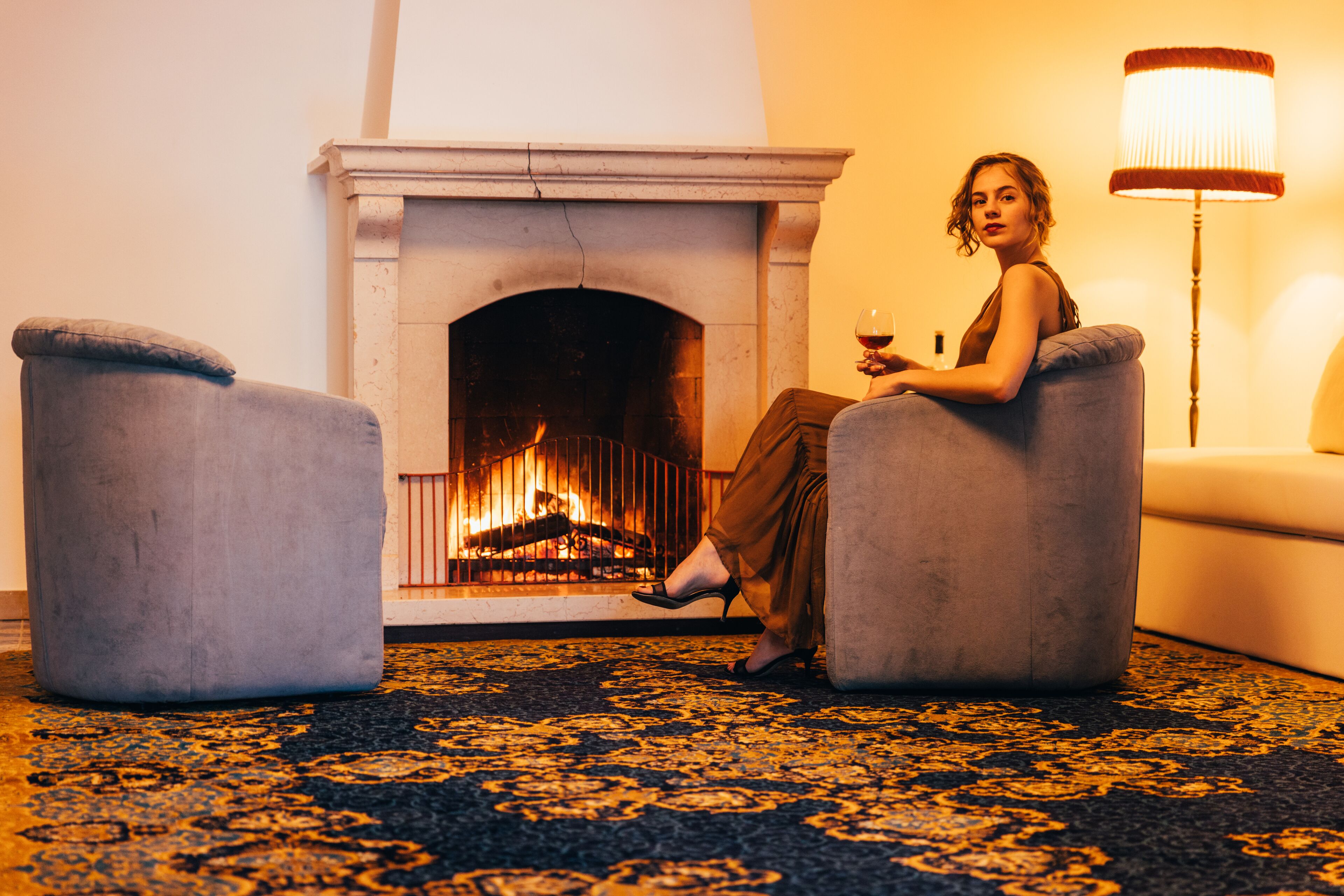 A person sitting on a sofa in front of a fireplace with a lit fire.