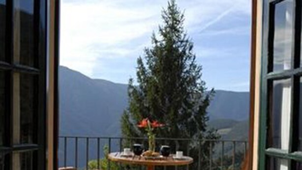 An open balcony with a table and two chairs, offering a view of a mountain and a tree. - Husa Sant Bernat (Montseny)