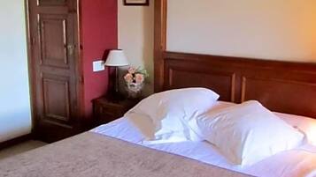 Una habitación de hotel con una cama grande, cabecera de madera, mesita de noche con lámpara y un cuadro enmarcado en la pared.