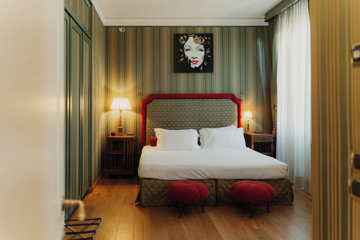 A neatly arranged bedroom with a large bed, two bedside tables with lamps, and a wall-mounted artwork.