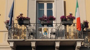 A building facade with a balcony, a window with shutters, and a flag. - Hotel Palazzo Guiscardo (Pietrasanta)