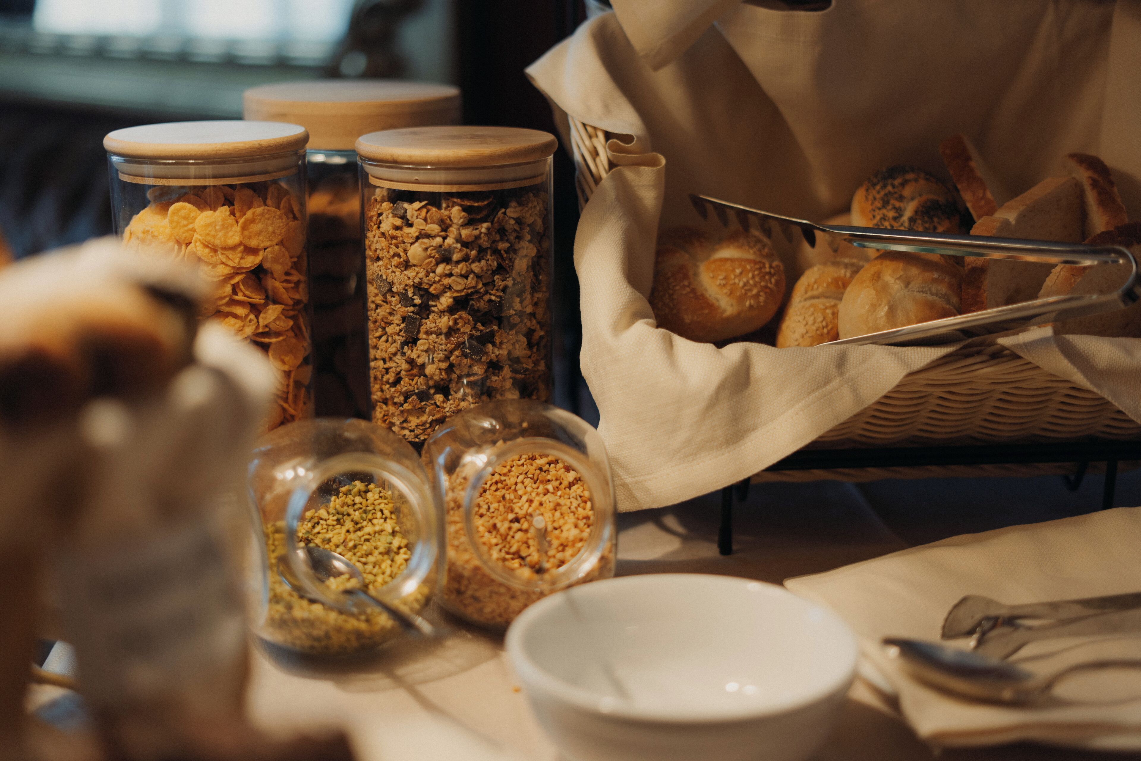 Une table avec des bocaux de granola et un panier de pain.
