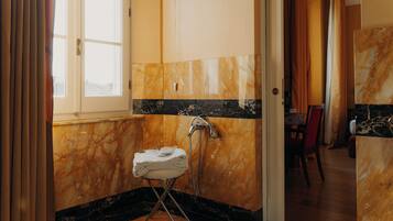 A bathroom with a marble wall, a towel rack, and a shower.