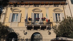 A historic building with a balcony, arched windows, and flags. - Hotel Palazzo Guiscardo (Pietrasanta)