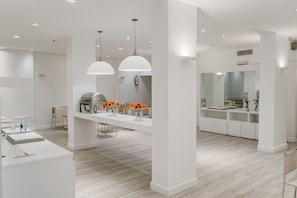 A modern kitchen with white cabinetry, a central island, pendant lighting, and a large mirror. - RH Rochester Concept (Buenos Aires)