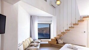 Une chambre d’hôtel moderne dotée d’une grande fenêtre, d’une banquette intégrée avec des coussins, d’un lit avec des serviettes soigneusement pliées et d’un escalier en bois original.