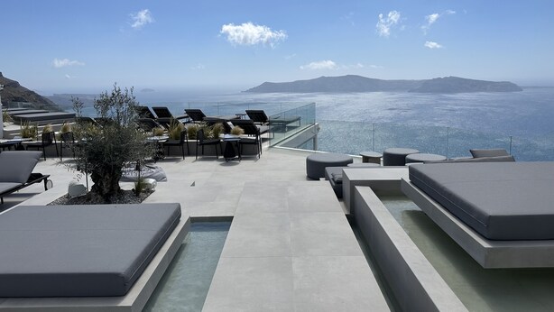 Une terrasse sur le toit, avec des chaises longues, un petit arbre et une piscine.