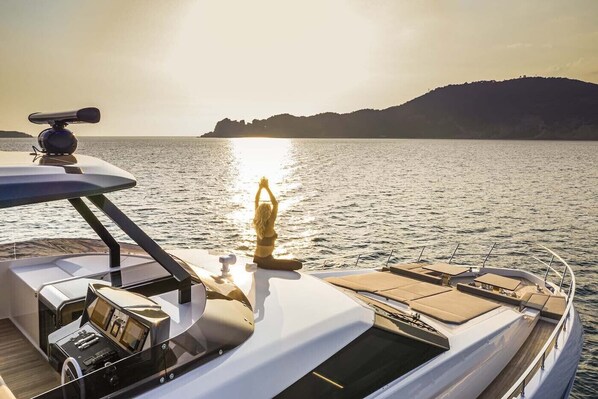 A yacht with a sun deck, a steering wheel, and a person meditating. - Rocabella Santorini Hotel & SPA (Santorini)