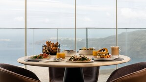 Une table à manger dressée pour le petit-déjeuner, avec une vue sur l’océan.