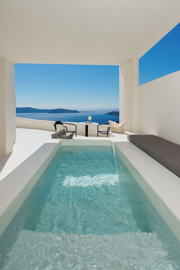 Zona de piscina con vista al mar y un espacio para sentarse.