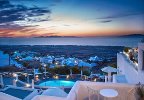 Un complexe hôtelier doté d’une piscine, d’un espace extérieur aménagé et offrant une vue sur la mer et la ville au crépuscule.