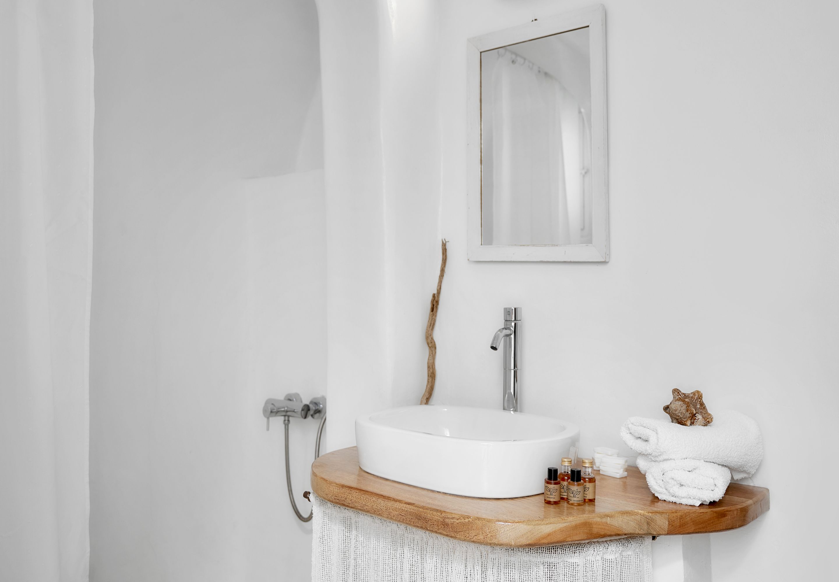 A bathroom with a white sink, wooden countertop, and a mirror.