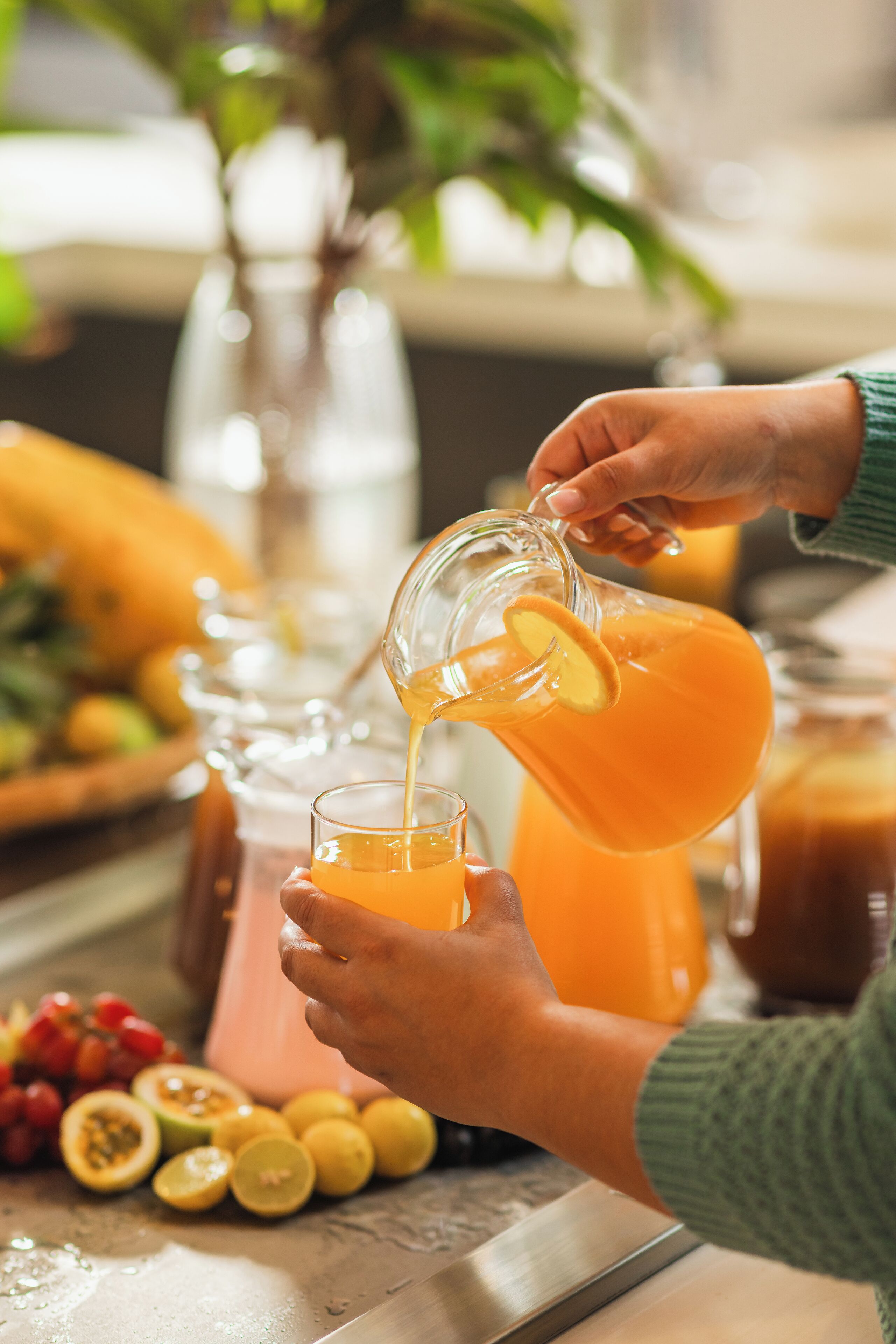 Une personne verse du jus d’orange dans un verre.