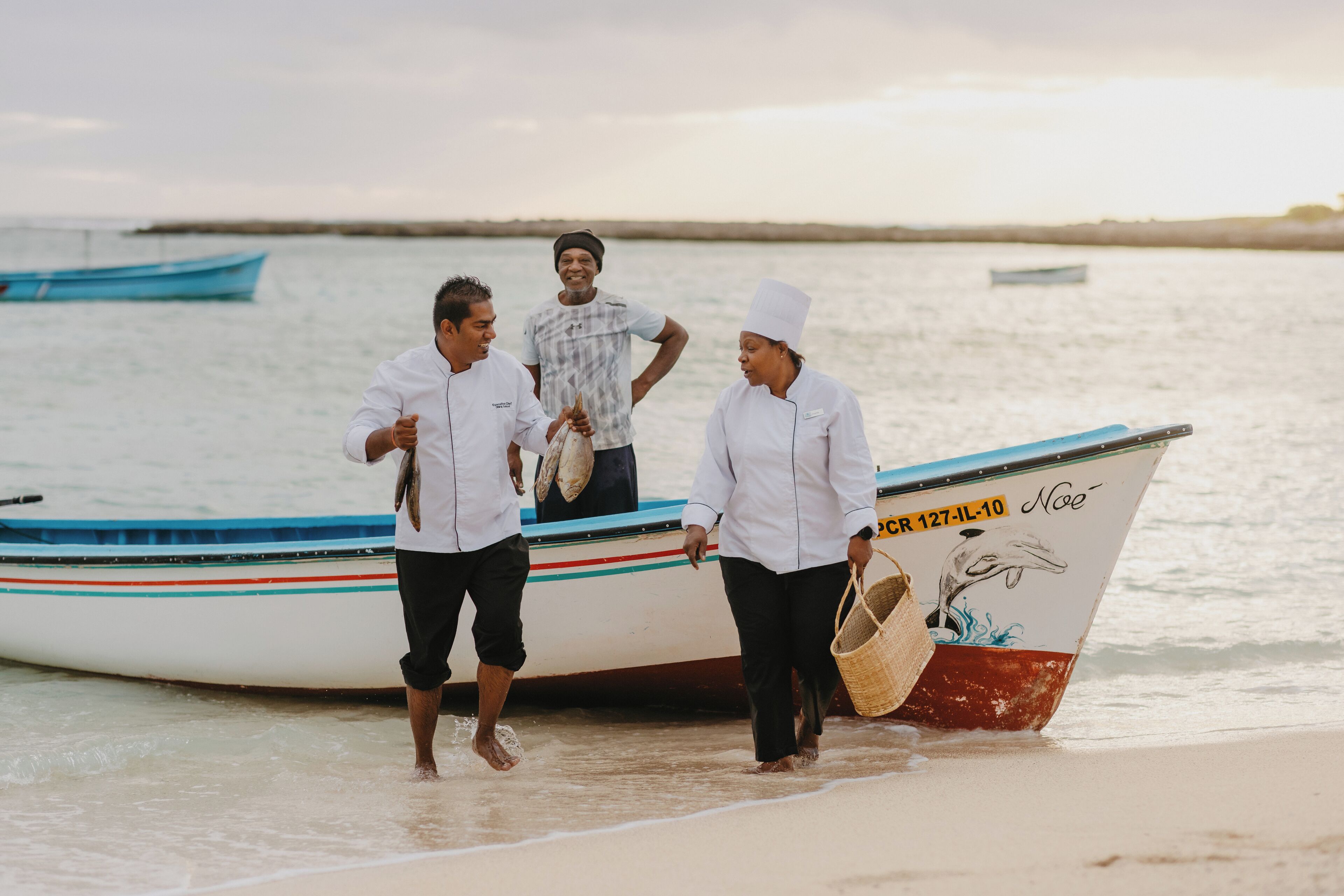 Three people near a boat on a beach.