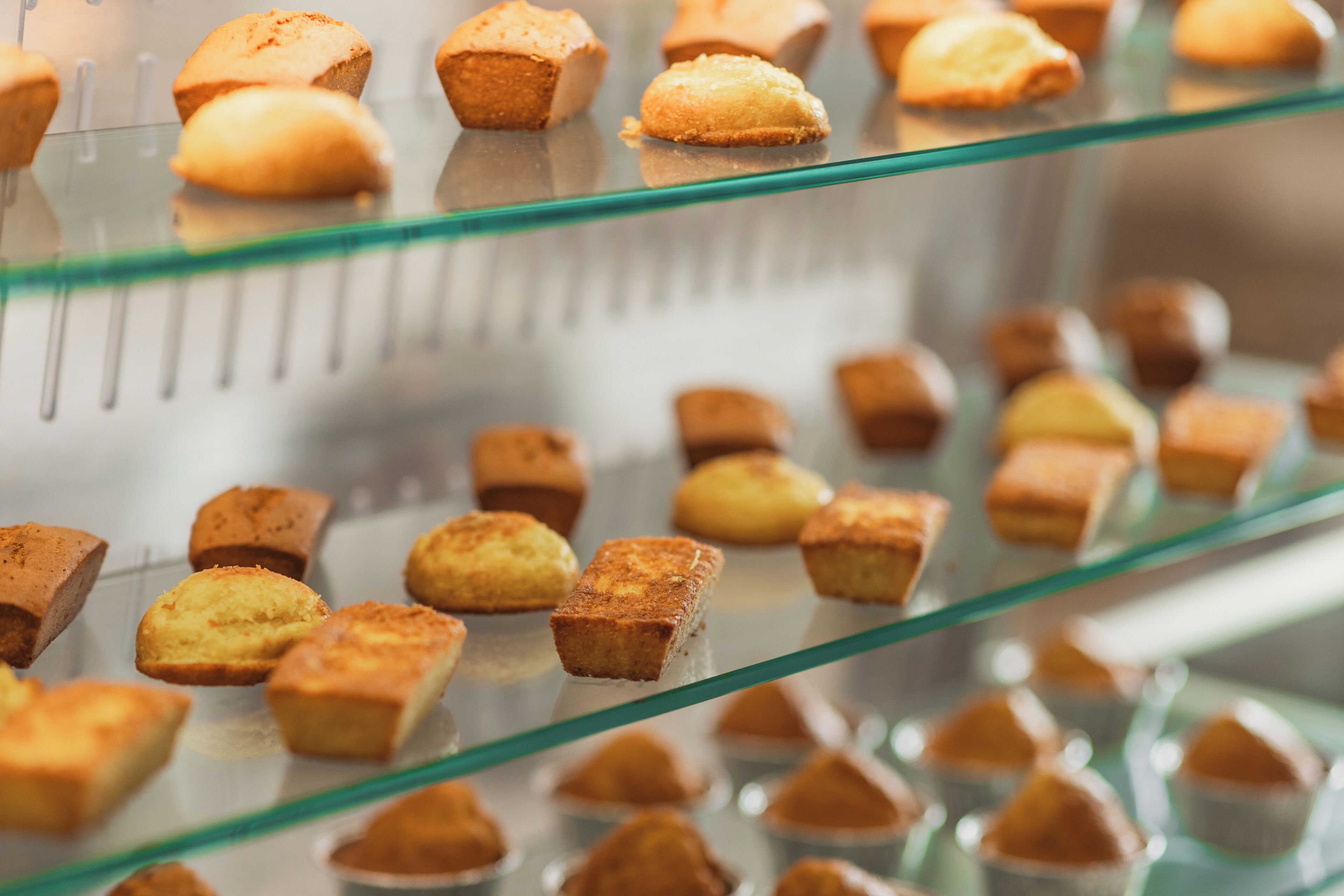 A display of various pastries on glass shelves.