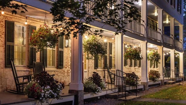 A two-story house with a covered porch, brick walls, and hanging flower baskets. - Grafton Inn (Grafton)